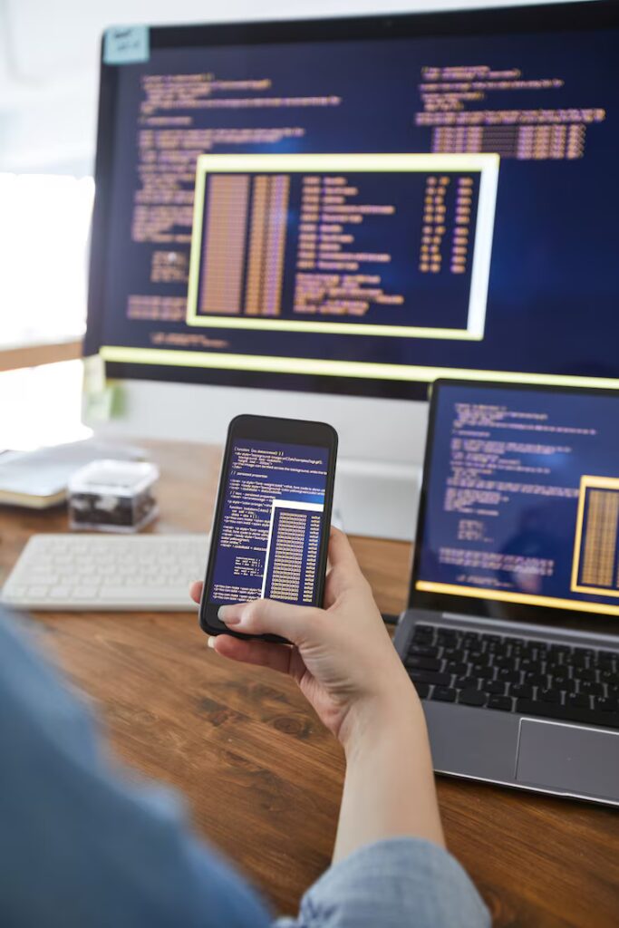Vertical close up female hand holding smartphone with code screen while working desk office female it developer concept copy space 236854 23791 683x1024